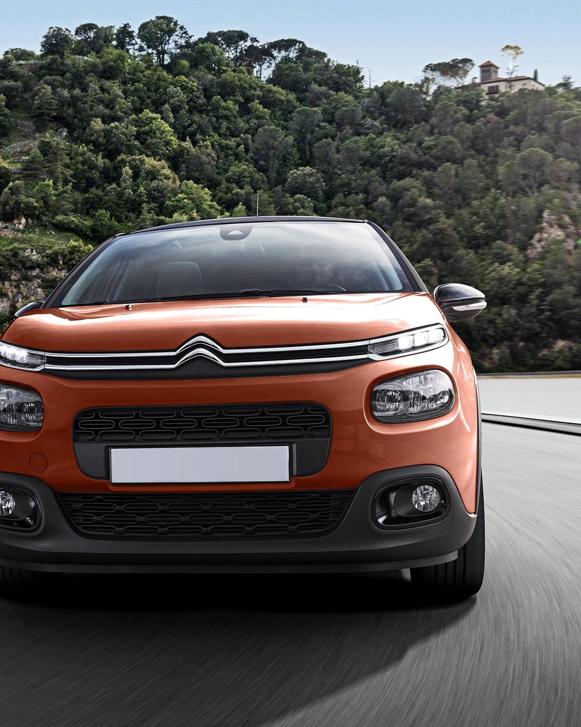 En orange Citroën C3 framifrån på en väg.