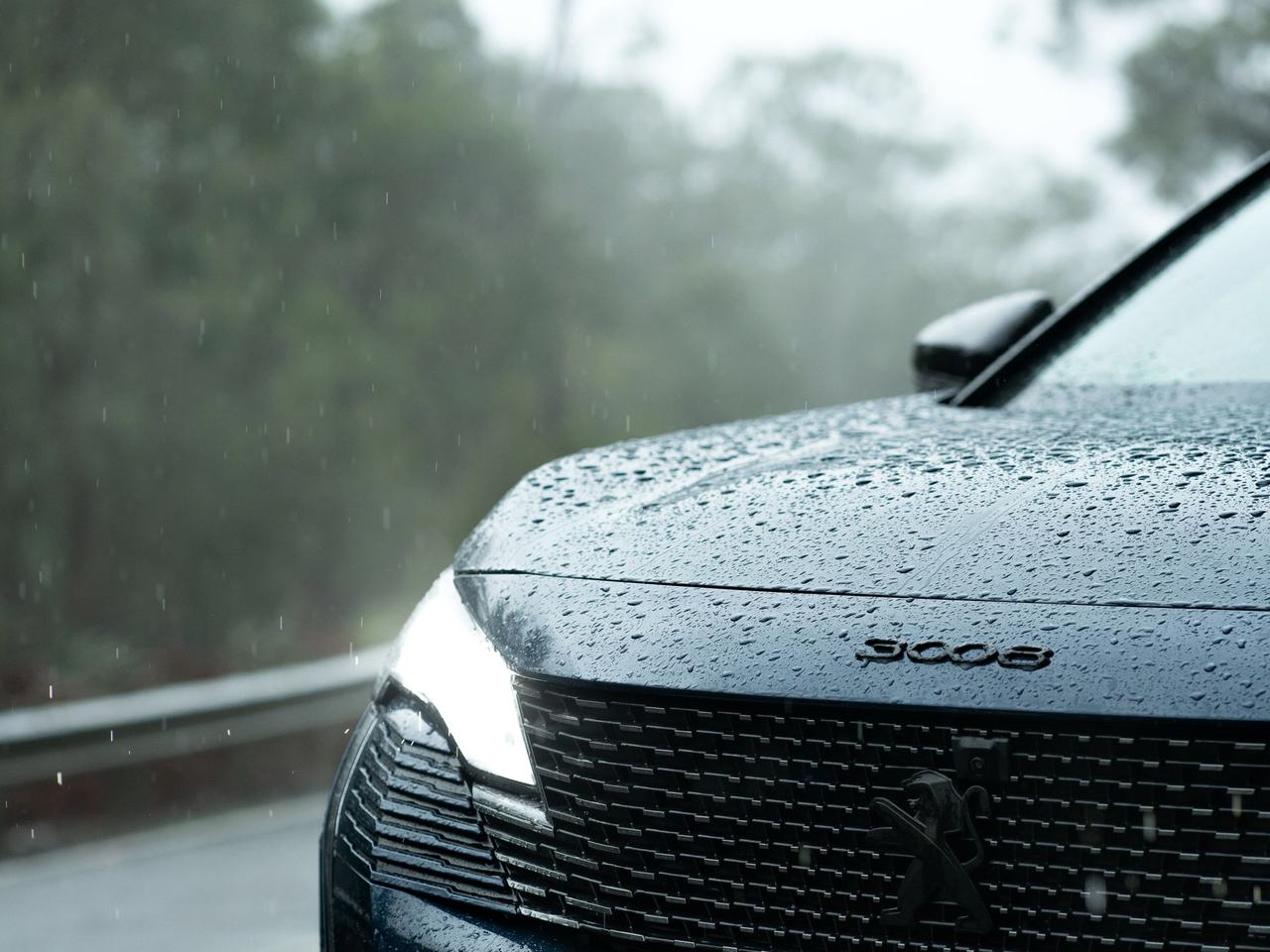 Fronten på en mörk Peugeot 3008 med regndroppar på motorhuven.
